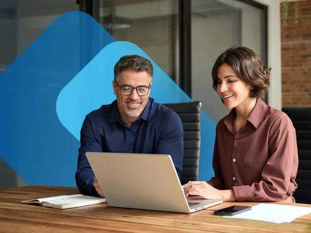 Coworkers looking at a laptop together 