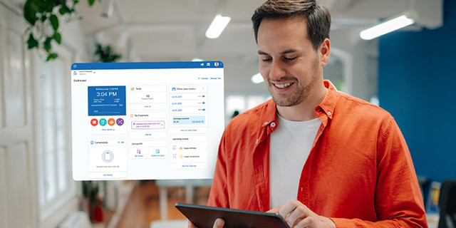 A person stands indoors holding a tablet and looking at the screen, with a translucent digital dashboard interface displayed beside them in a modern office setting.