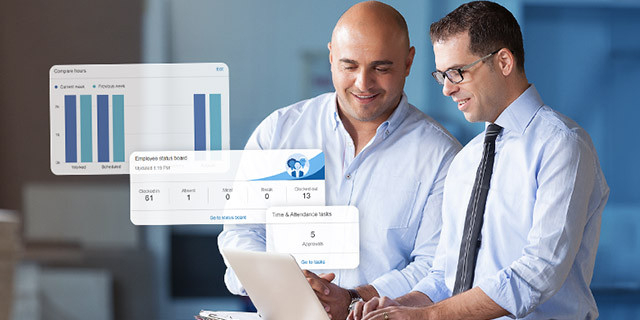 Two people stand together looking at a tablet, with translucent charts and time-and-attendance analytics displayed beside them in a modern office setting.