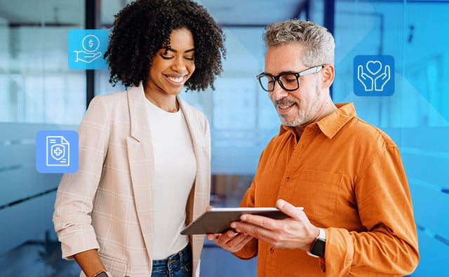 Two people in a modern office review information on a tablet, surrounded by digital healthcare-themed icons representing benefits, wellness, and coverage.