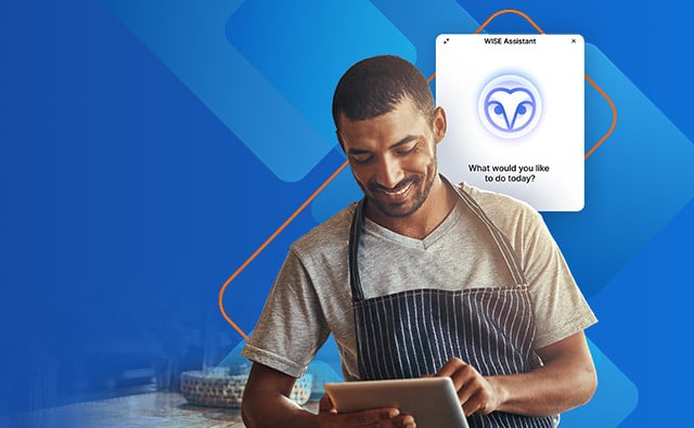 Person wearing an apron using a tablet with a WISE Assistant interface displayed nearby against a blue geometric background.