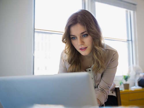 Young woman looking at laptop in small office